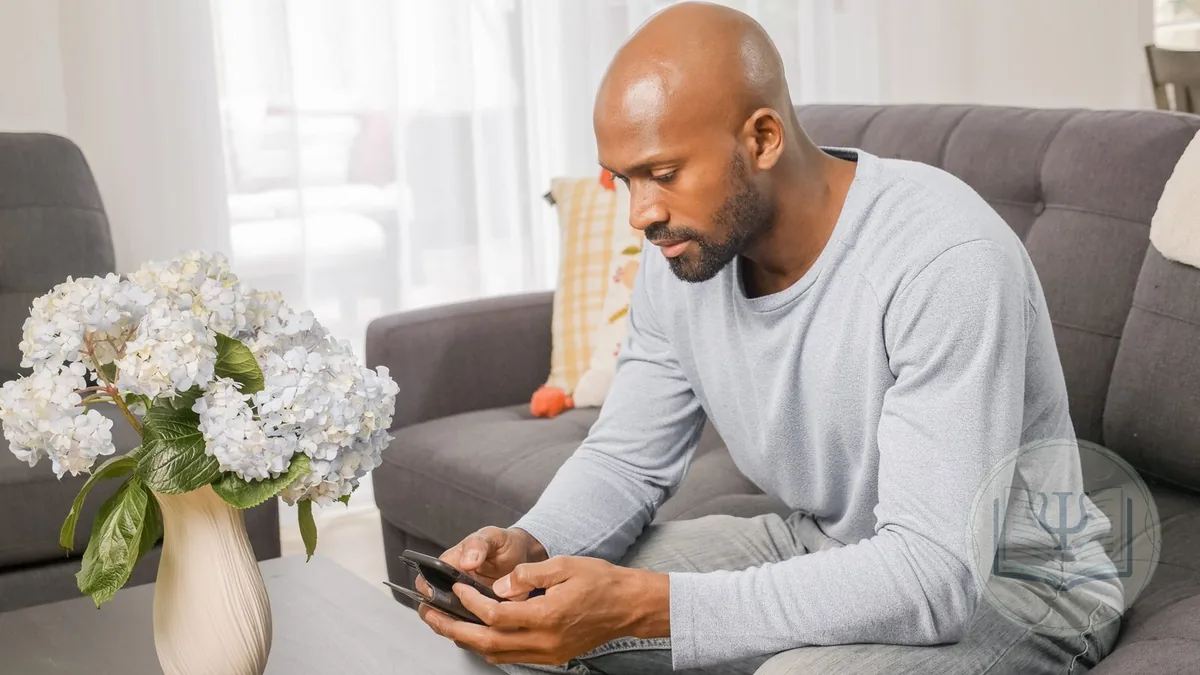 Client sitting on the sofa at home filling in a therapy intake form on a phone before the first session