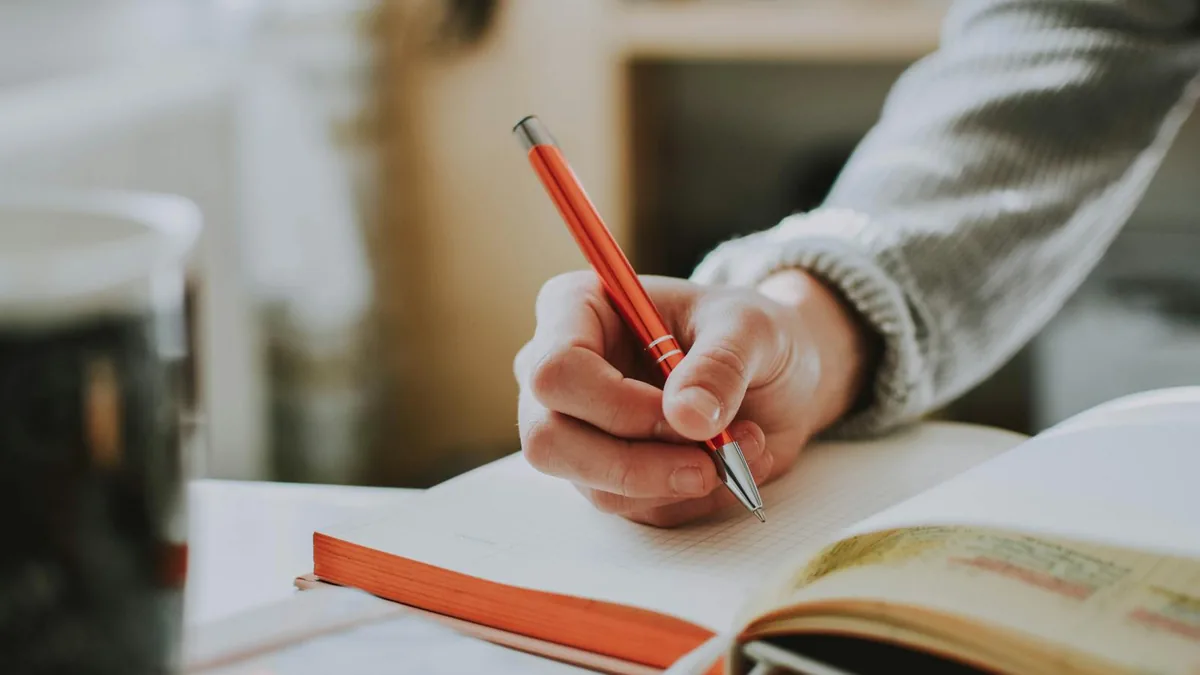 Psicólogo escribiendo notas de sesión SOAP en un cuaderno clínico — registro de sesión de psicología