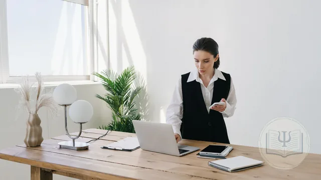 Psicóloga consultando su agenda en el portátil y el móvil sobre la mesa de su despacho, con un software para psicólogos en la nube